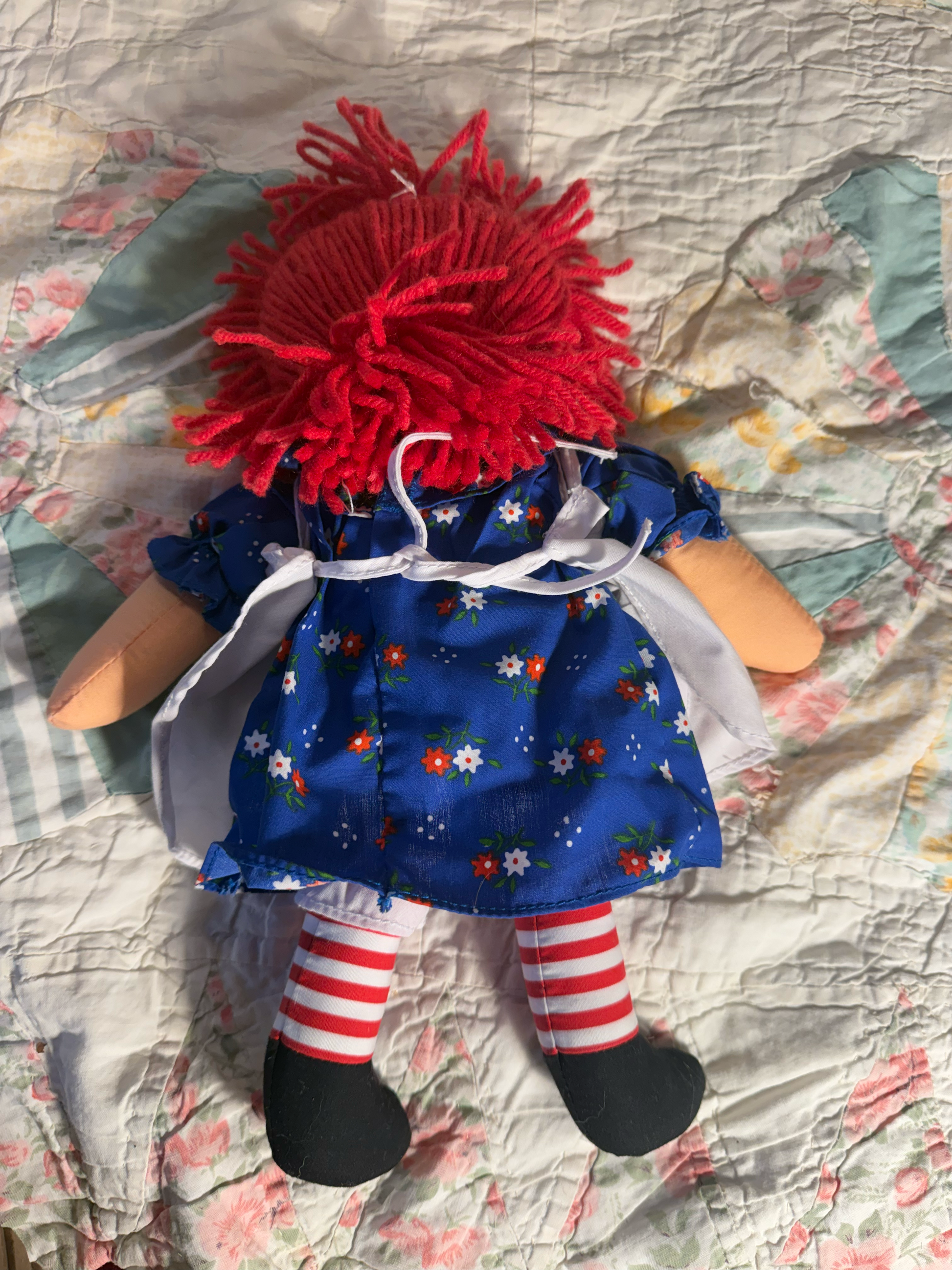 Toy figure with a red pom-pom on a patterned fabric background